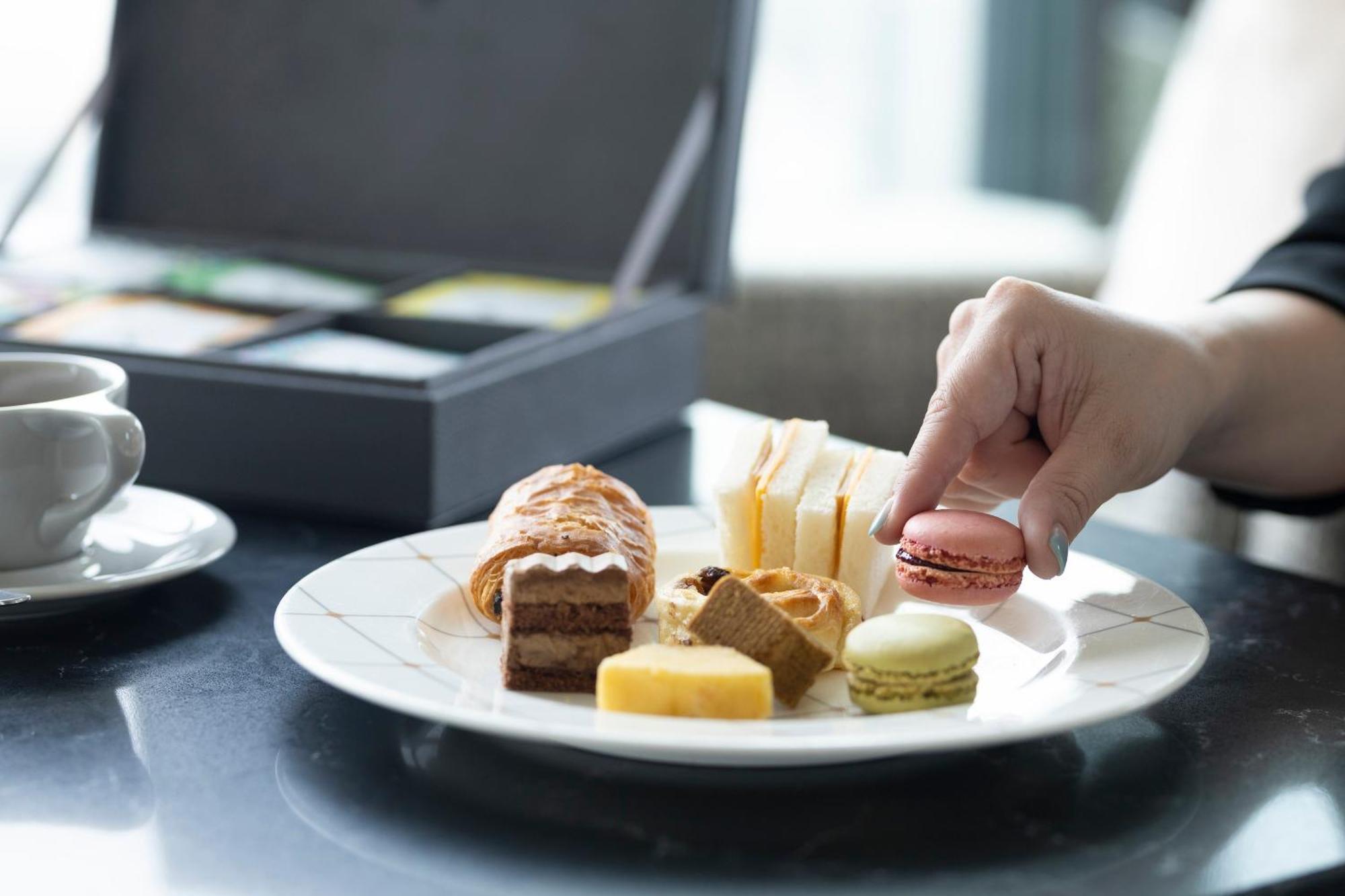The Royal Park Hotel Iconic Osaka Midosuji Dış mekan fotoğraf A woman eating a plate of petit fours